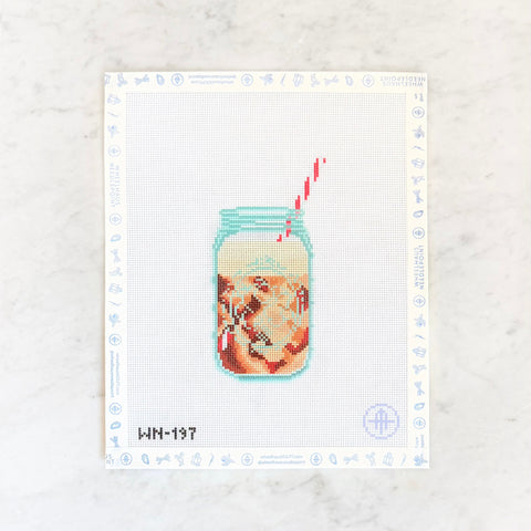 Needlepoint design of a frothy iced coffee in a canning jar with a straw on a white background.
