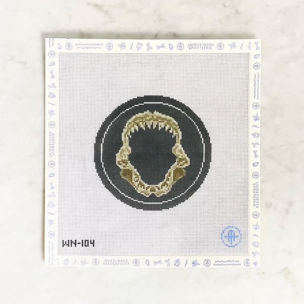 Needlepoint design on 18 mesh with a black circle, shark jaw, on a marble surface.